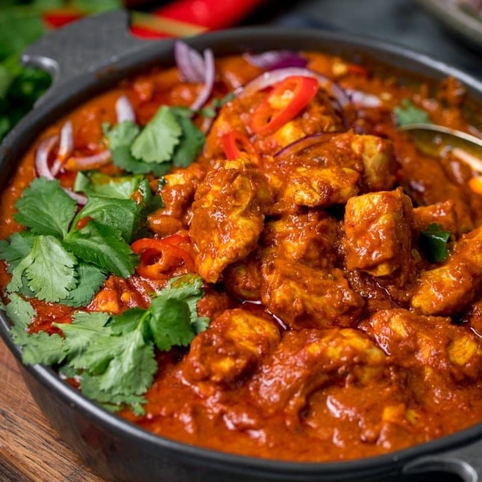 Tikka and Grill's chicken tikka masala, garnished with fresh cilantro, red onions, and chili slices.